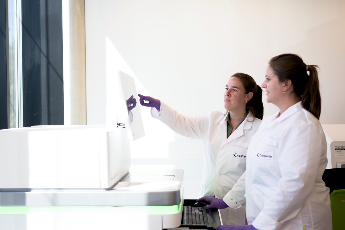 Two scientists working at a laboratory instrument.
